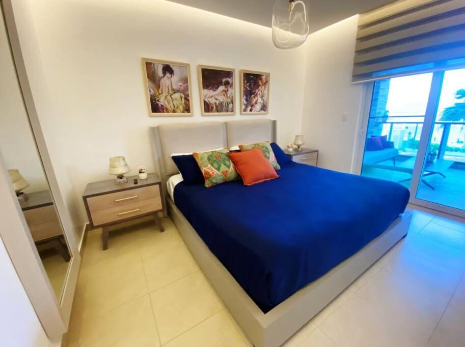 a bedroom with a blue bed with a night stand and a window at Lugar encantador con alberca frente al mar. in Sosúa