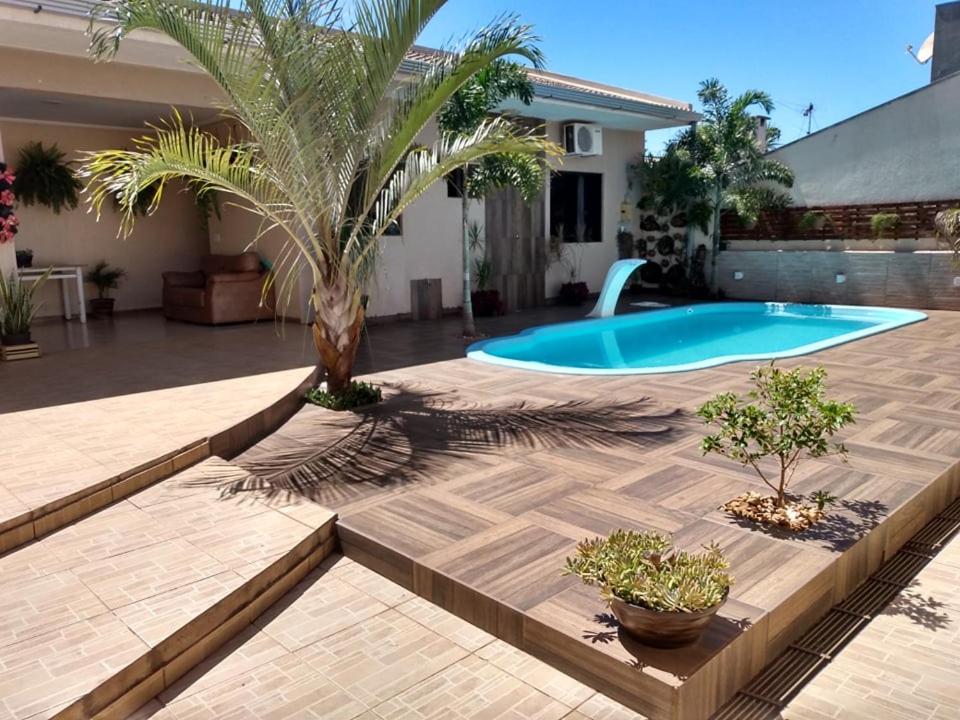 un patio trasero con una piscina y una palmera en Edicula com um quarto banheiro e piscina e lazer, en Foz do Iguaçu