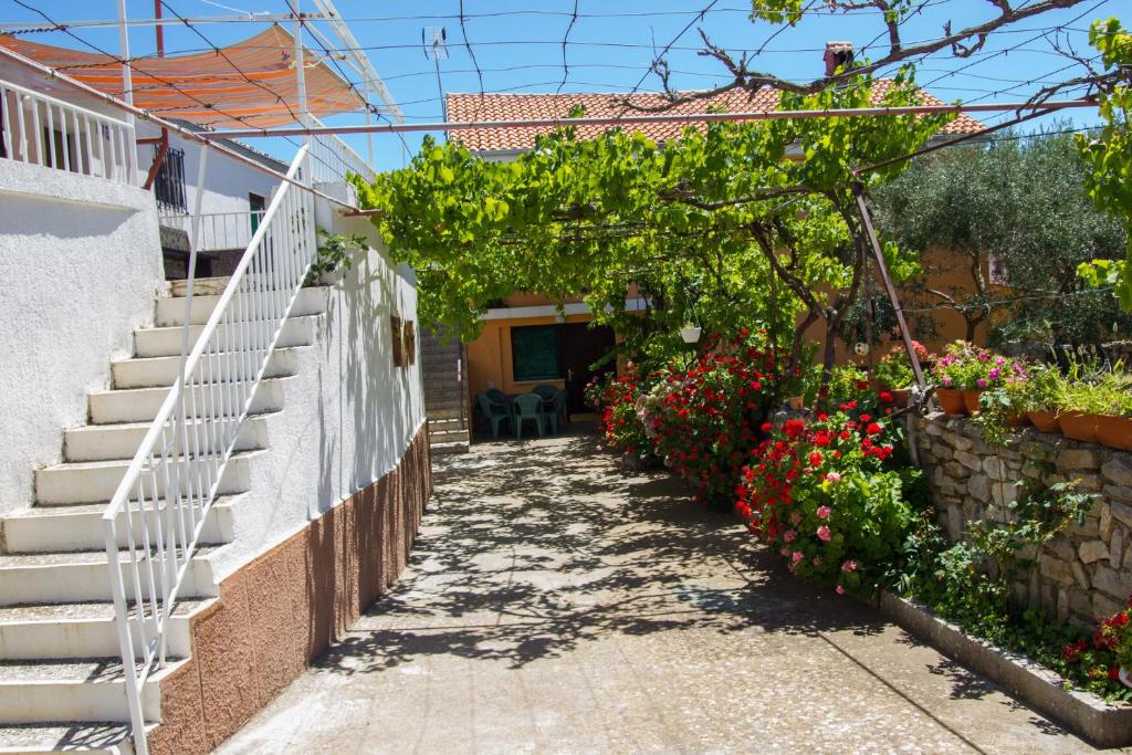 a pathway leading to a house with flowers at Apartments Stefanovski Paradiso in Veli Lošinj
