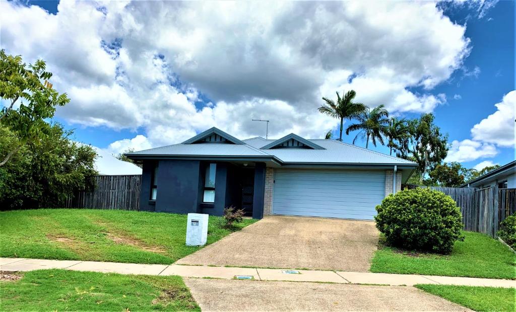 une maison bleue avec un garage et une clôture dans l'établissement Modern 4BR close to the Airport- Whole house, à Gladstone