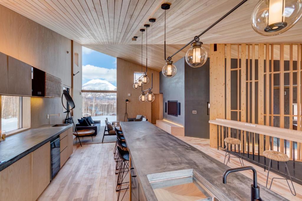 a kitchen with a long counter and a living room at Foxwood E by H2 Life in Niseko