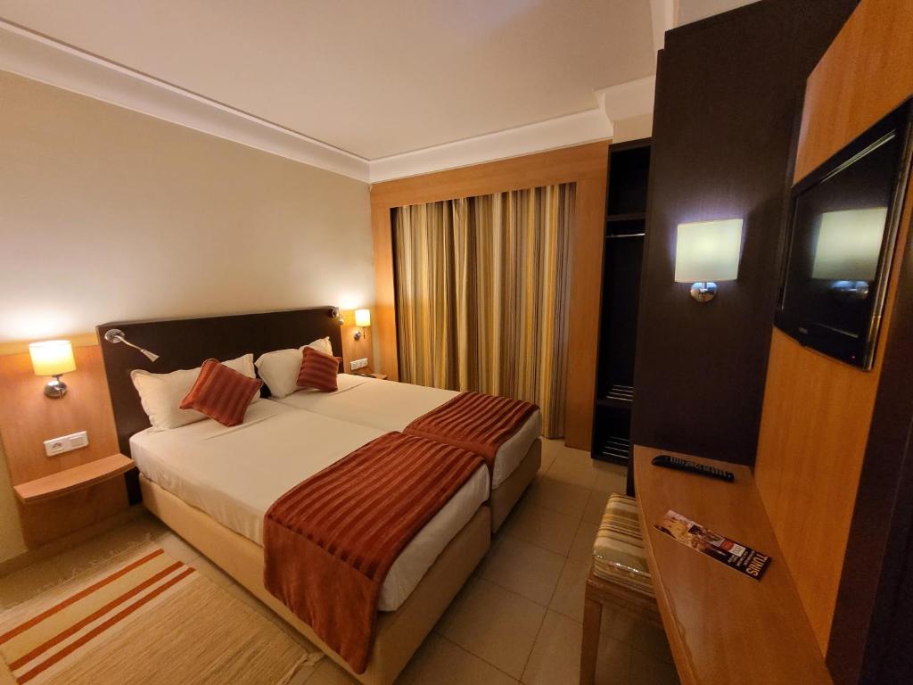 una habitación de hotel con una cama y un televisor en Hotel Tiba, en Túnez