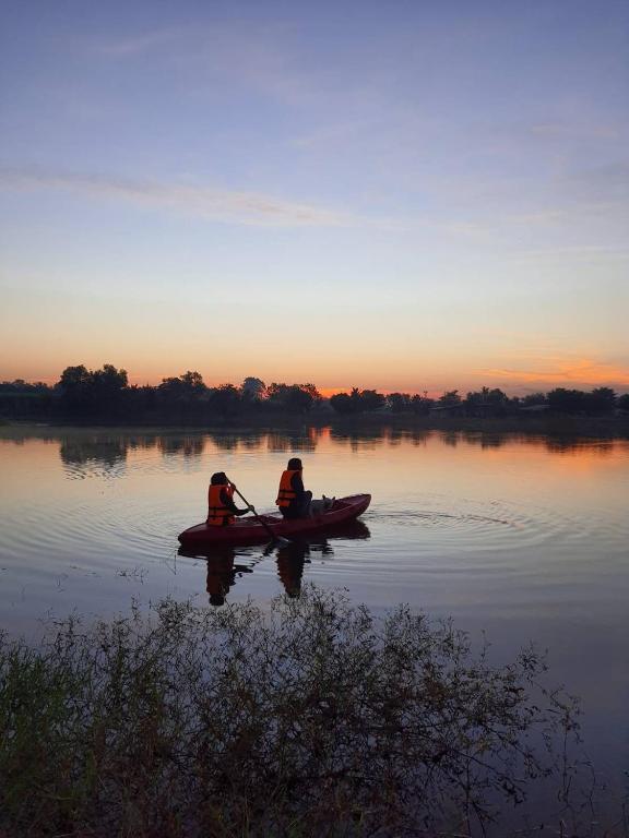 two people in a kayak on a lake at sunset at ทุ่งดินดำ Farm Stay in Ban Kho Wang