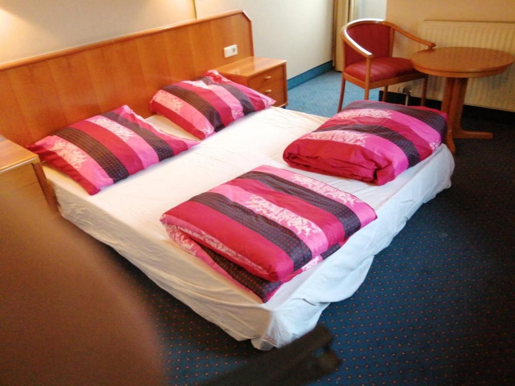 ein Bett mit rosa und schwarzen Kissen darauf in der Unterkunft apartment Lampertheim in Lampertheim