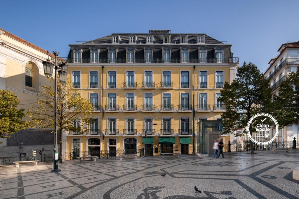un grande edificio giallo con un cartello di fronte di Bairro Alto Hotel a Lisbona