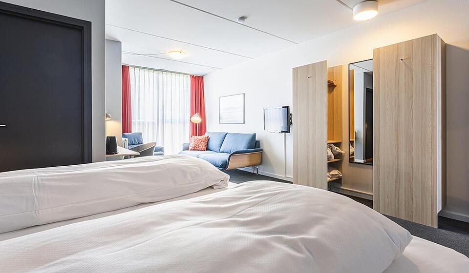 um quarto de hotel com uma cama grande e um sofá em Skaga Hotel em Hirtshals