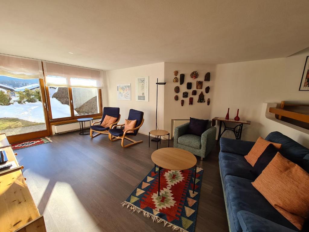sala de estar con sofá azul y sillas en Alpen-fewo, Denter Vias 10, Casa Alma, en Flims