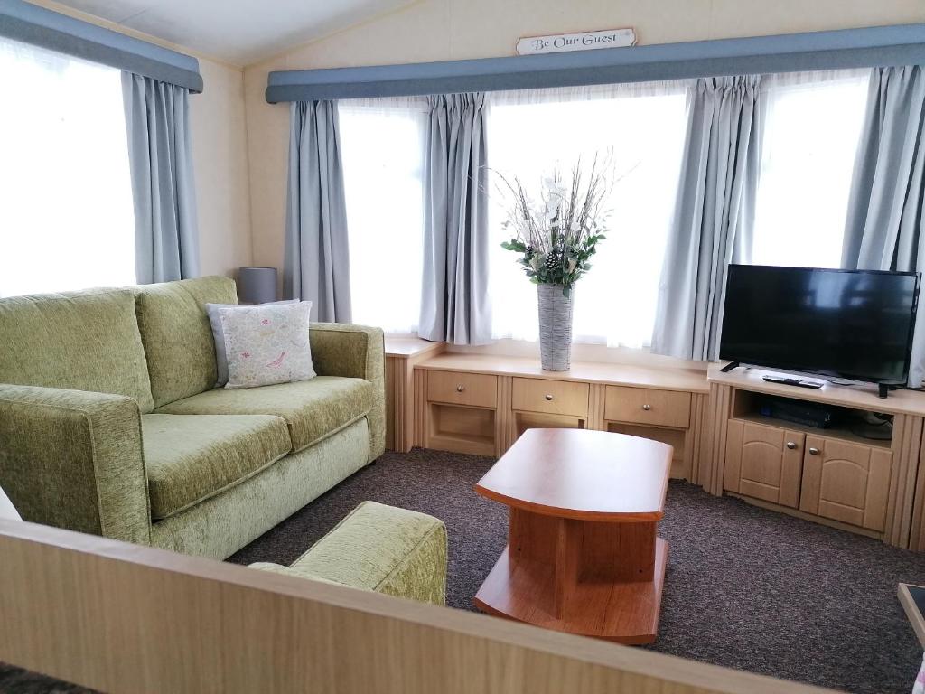 a living room with a couch and a tv at 2 Bed Static Caravan @ Hoburne Devon Bay in Paignton