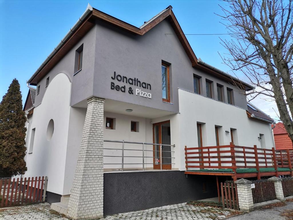 un edificio blanco con un letrero que lee cama de cuerno largo y comida en Jonathan Bed&Pizza en Komárom