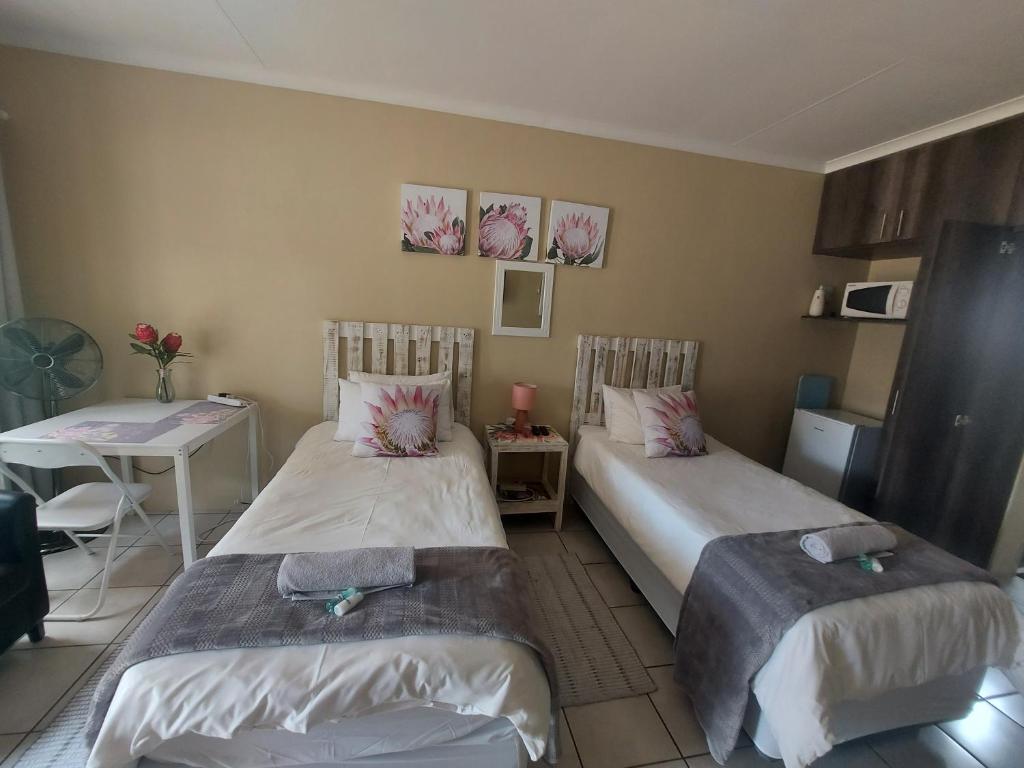 um quarto com duas camas e uma mesa e uma mesa em DeLutz Overnight Accommodation Room 2 em Polokwane