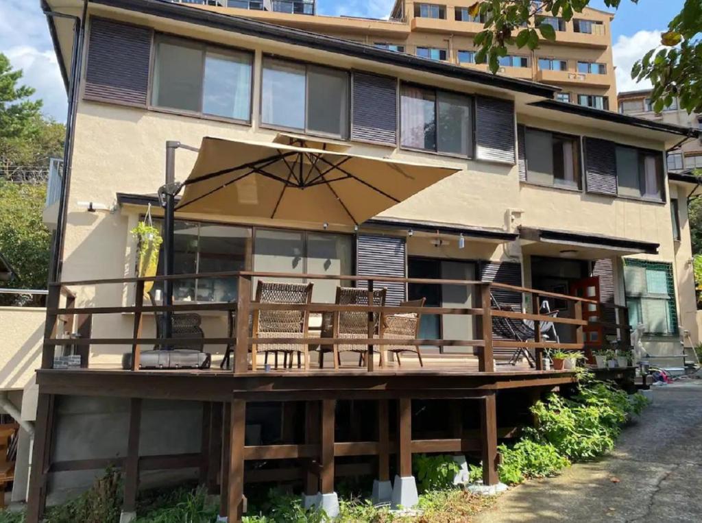 une maison avec une terrasse dotée de chaises et d'un parasol dans l'établissement 遙かな亭, à Numazu