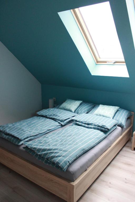 a bed in a blue room with a skylight at Apartament Nad Góralem in Milówka