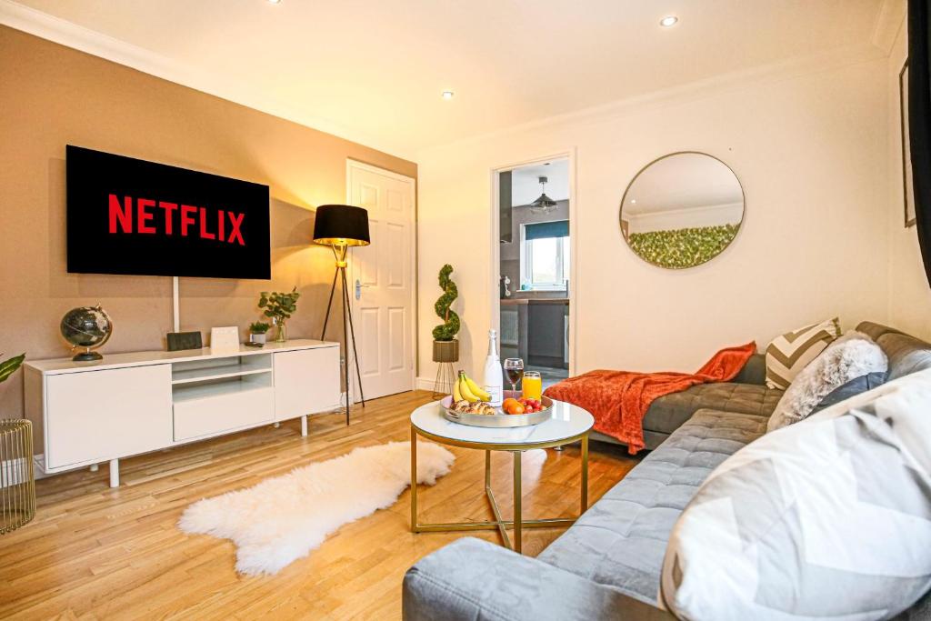 a living room with a couch and a tv at Pannier House - Central MK - Free Parking, Garden, Smart TVs with Netflix by Yoko Property in Milton Keynes