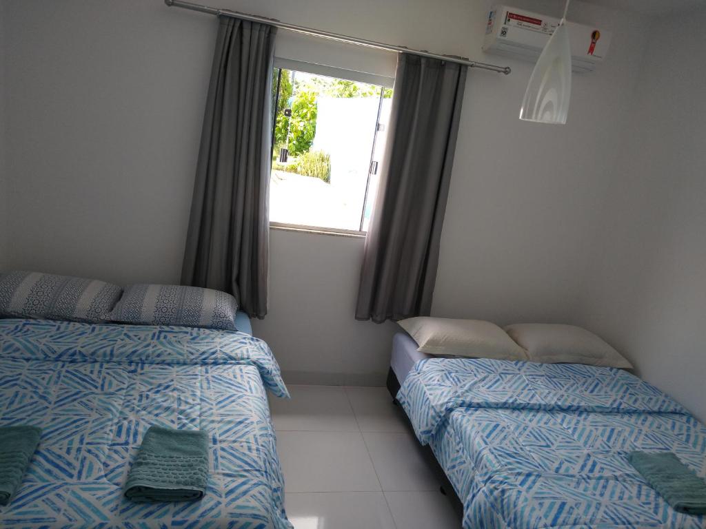 two beds in a room with a window at Casa azul in Barra do Garças