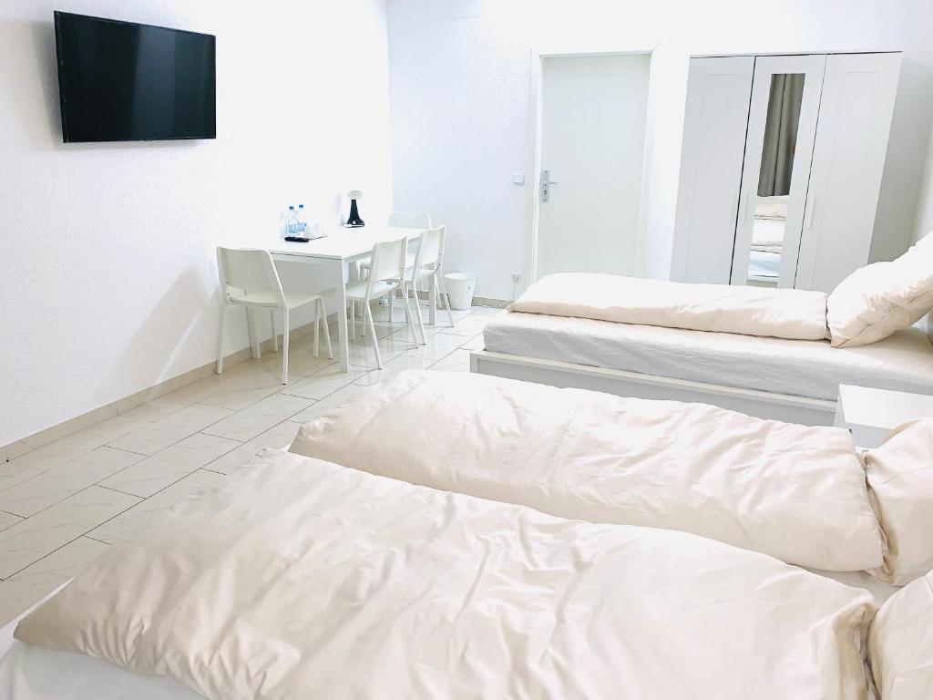 a white room with two beds and a table at Ganzes Apartment 20 min vom Frankfurt HBF in Langen