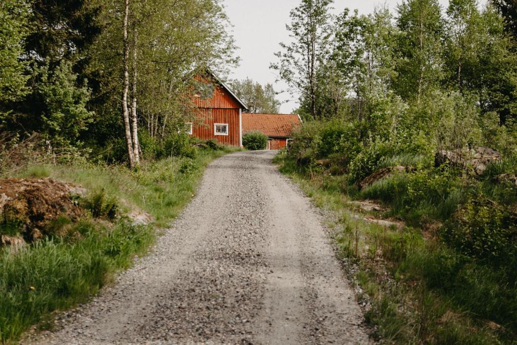 eine unbefestigte Straße vor einer roten Scheune in der Unterkunft En lantlig idyll med skogen precis utanför dörren! in Ullared