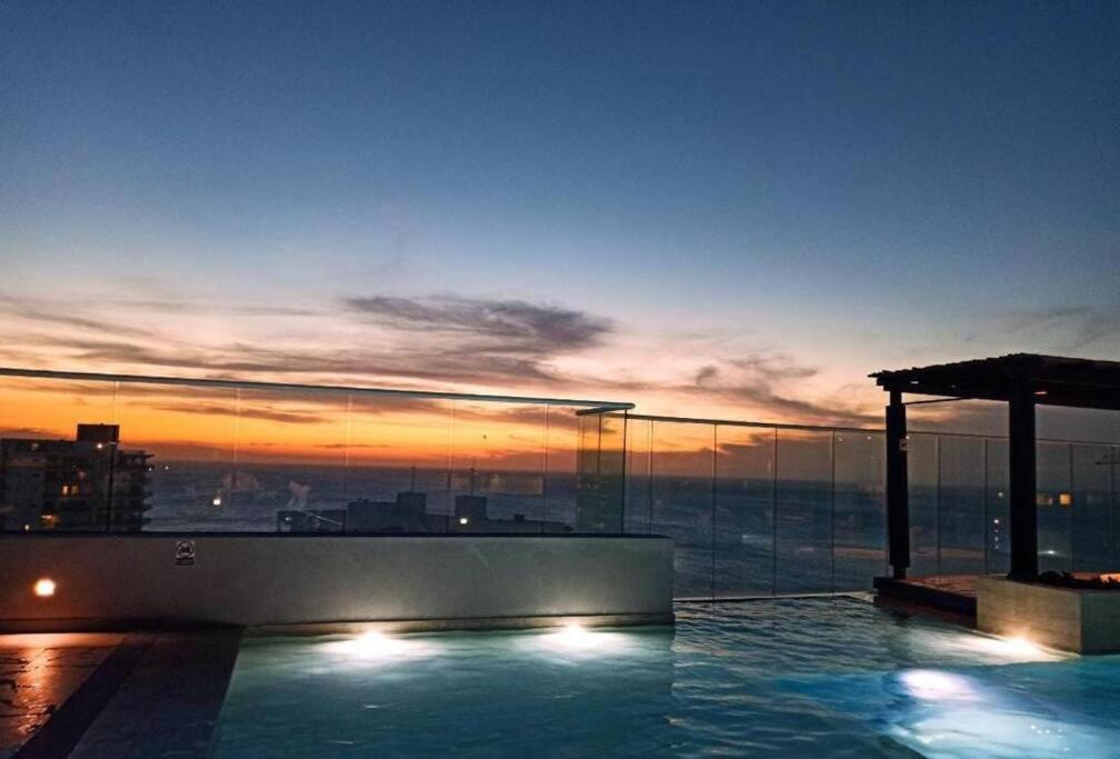 a pool on the roof of a building with a sunset at Edificio Reserva del Mar, Paya Salguero , Santa marta in Gaira