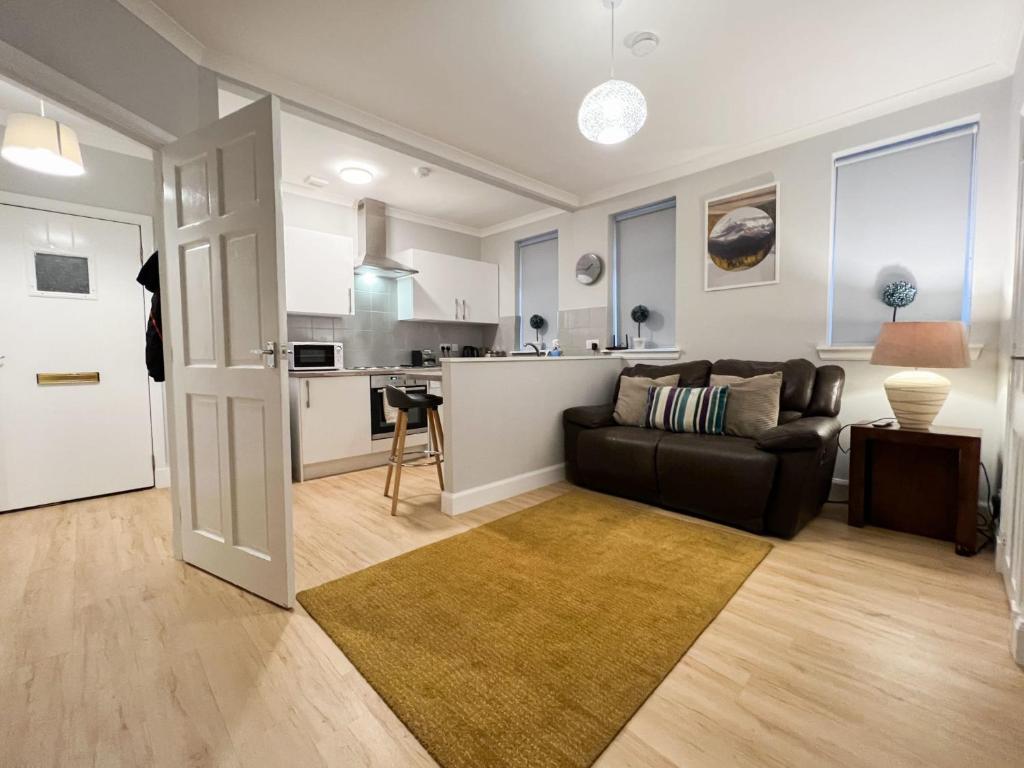 ein Wohnzimmer mit einem Sofa und einer Küche in der Unterkunft Glasgow 2 Bedroom Apartment in Glasgow