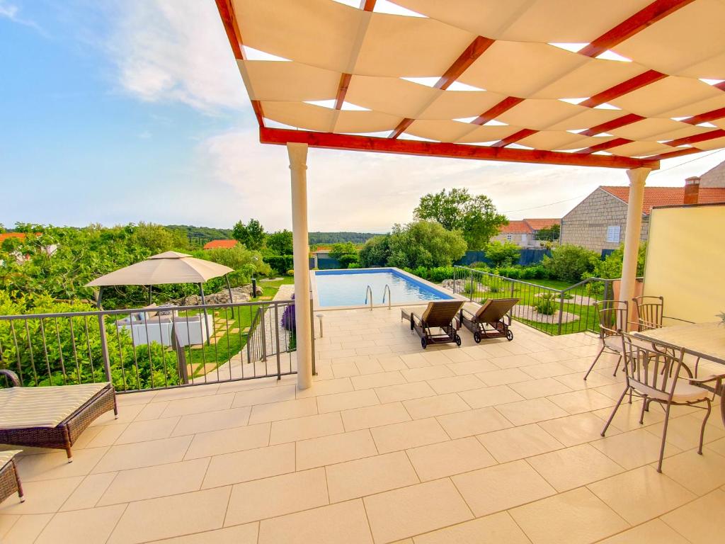 eine Terrasse mit einem Tisch, Stühlen und einem Pool in der Unterkunft Villa Sun in Čilipi