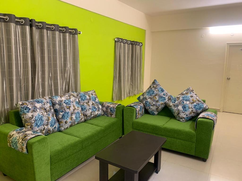 uma sala de estar com um sofá verde e uma mesa em Homewood Suites ( Service Apartments) em Hyderabad
