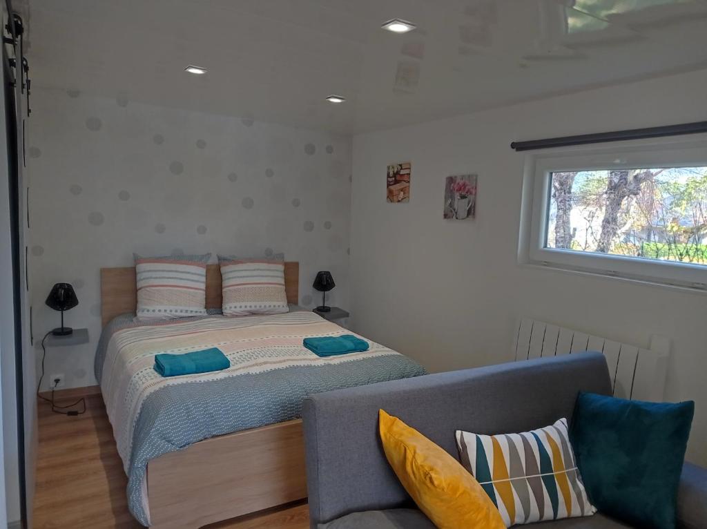 a bed in a room with a couch and a window at L alouette in Égletons