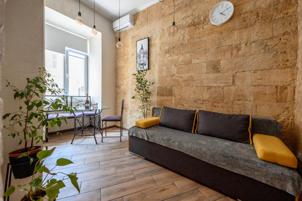 a living room with a couch and a brick wall at Уютная квартира недалеко от Дерибасовской in Odesa
