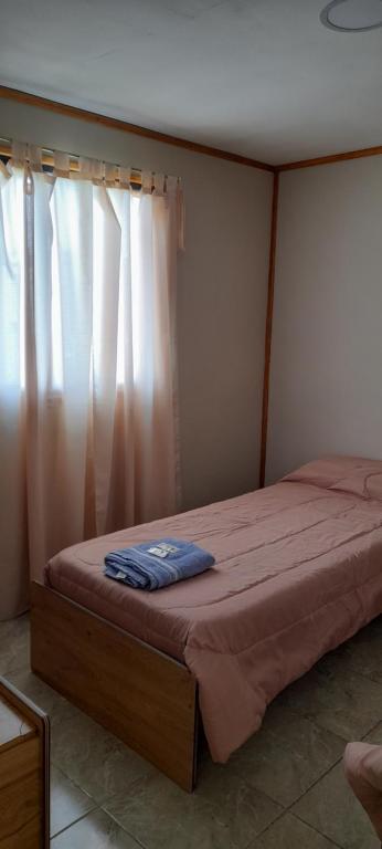 1 cama en un dormitorio con ventana en M&M l en Comodoro Rivadavia