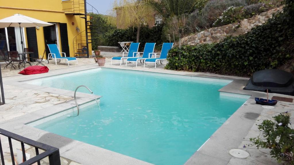 una gran piscina con sillas azules en un patio en Holiday Paraiso, en Sant Antoni de Calonge
