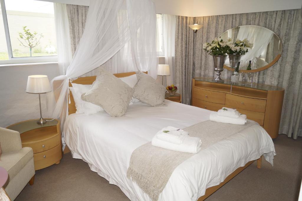 a bedroom with a white bed with a mirror at Valentines Hermanus in Hermanus