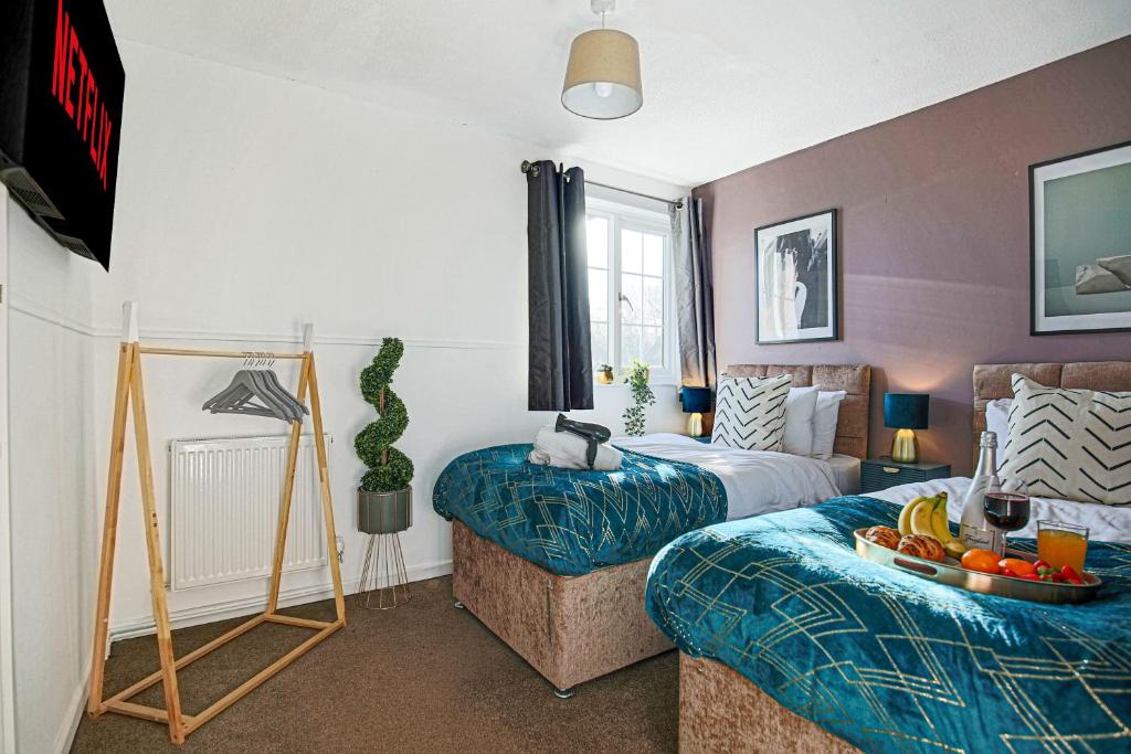Un dormitorio con 2 camas y una mesa con un bol de fruta en Petworth House - Central Milton Keynes - Smart TVs, Pool Table, Garden and Free Parking by Yoko Property, en Milton Keynes