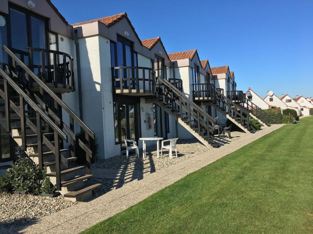 a row of houses with stairs and a bench at Genieten aan zee in De Haan in De Haan
