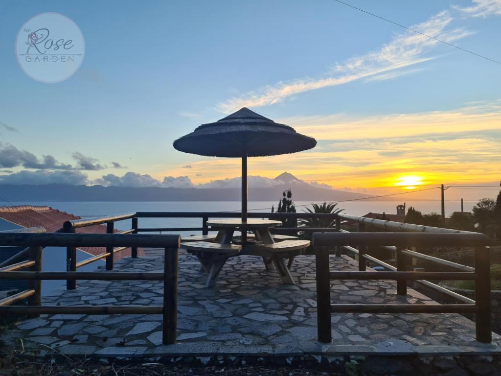 a picnic table with an umbrella in front of the ocean at Lucy's Rosegarden in Urzelina