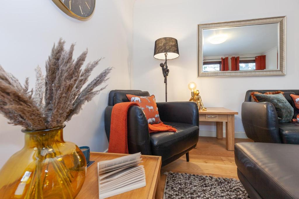 una sala de estar con 2 sillas y un jarrón sobre una mesa en Vibrant & bright city centre apartment! en Oxford