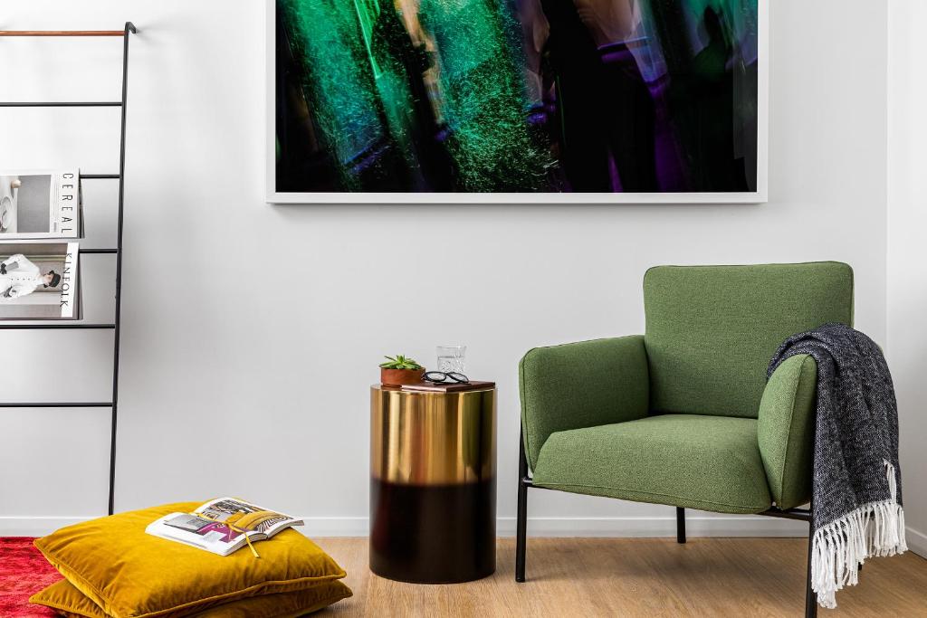 a living room with a green chair and a ottoman at  Liz by Black Swan - DC Executive Flat in Washington, D.C.