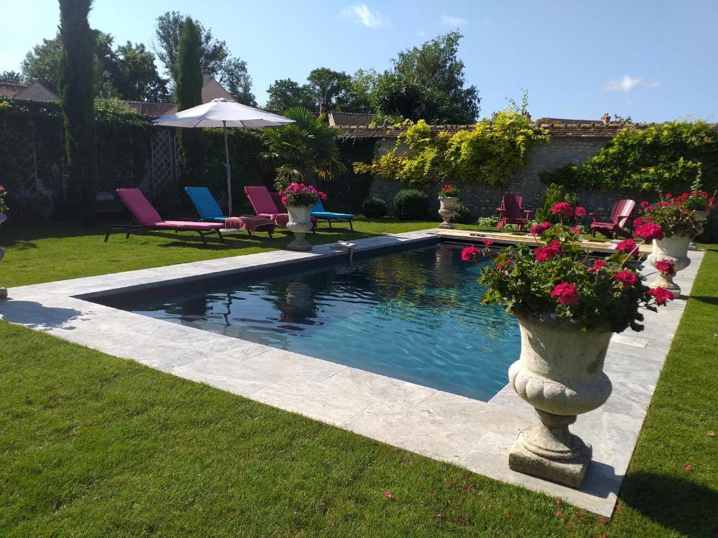 a swimming pool in a yard with chairs and flowers at Les Glycines in Ury