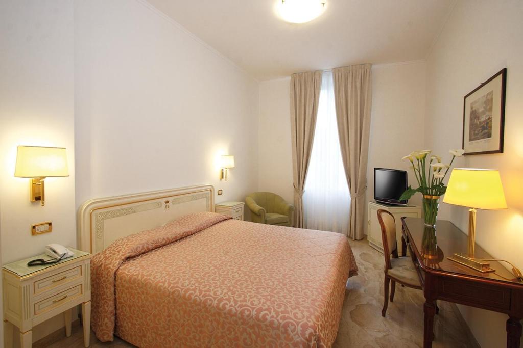 a hotel room with a bed and a table and a desk at Hotel Villa Elena in Varazze