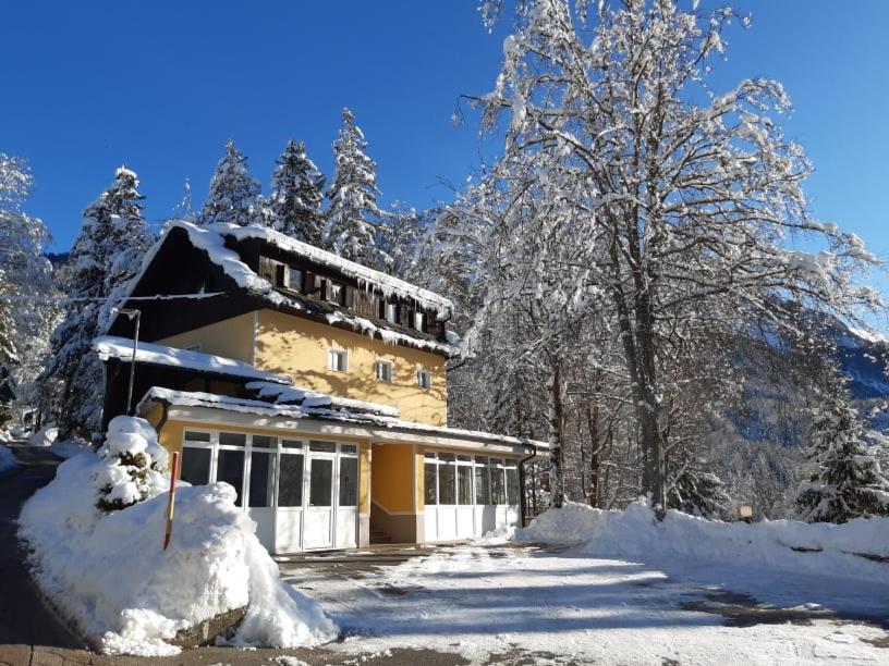 una casa cubierta de nieve con árboles en el fondo en Rooms Barovc by the Lake Jasna en Kranjska Gora