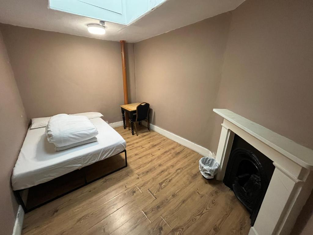 a small room with a bed and a fireplace at Queen Elizabeth Hostel in London