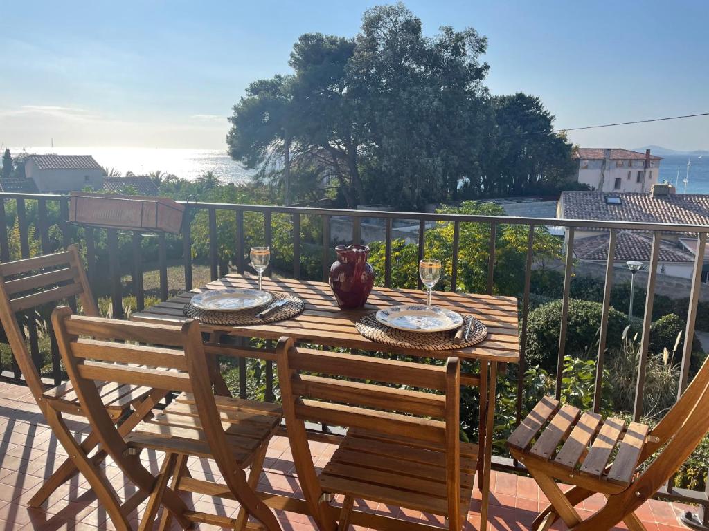 een houten tafel met stoelen en een vaas op een balkon bij Appartement cosy vue mer à 50 m de la plage - refait à neuf et climatisé in Le Pradet