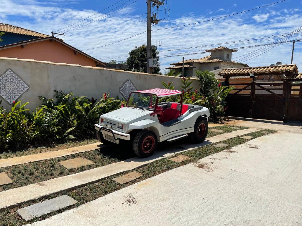 un carrito de golf blanco pequeño estacionado en una entrada en CASA BUZIOS PRAIA RASA, en Búzios