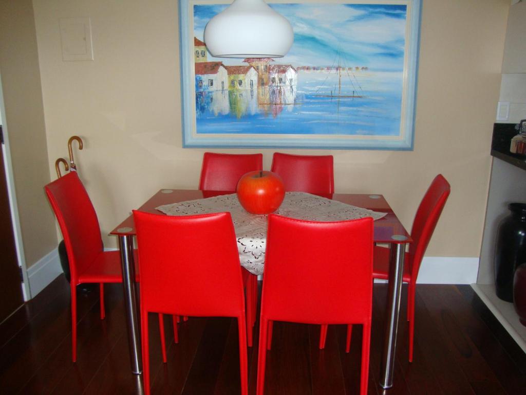 a dining room table with red chairs and an apple on it at Duplex em Gramado in Gramado