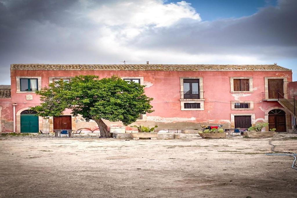 un edificio rosa con un árbol delante de él en Il Casale Apartament&Rooms, en Burgio