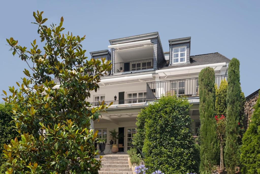 une grande maison blanche avec des arbres devant elle dans l'établissement Wein und Landhaus Kallfels, à Kröv