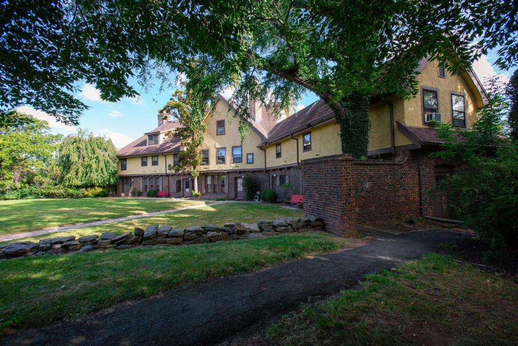 uma casa grande com uma árvore em frente em Rutgers University Inn and Conference Center em New Brunswick