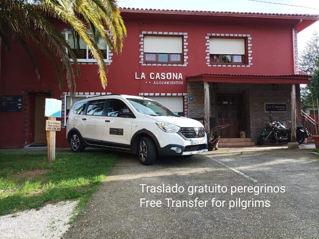 un coche blanco estacionado frente a un edificio rojo en La Casona de Betanzos, en Betanzos