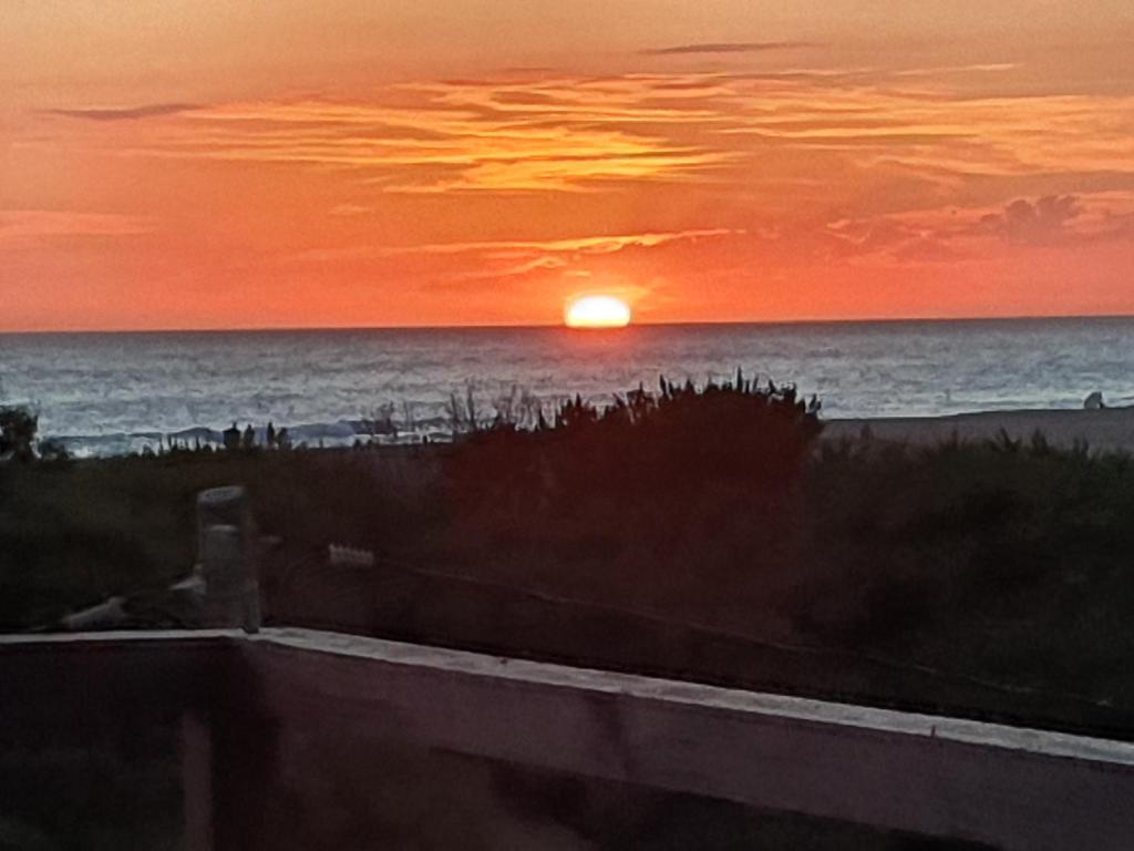 um pôr do sol na praia com o oceano ao fundo em Hotel Playa Chihuahua em Punta del Este