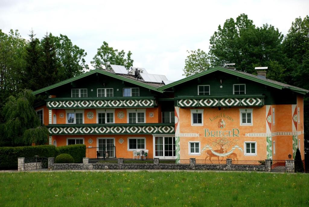 an orange and black building with a green yard at Landhaus Brieger in Henndorf am Wallersee