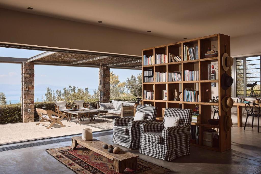 ein Wohnzimmer mit einem Bücherregal und Stühlen in der Unterkunft Aegina Retreat in Tzíkidhes