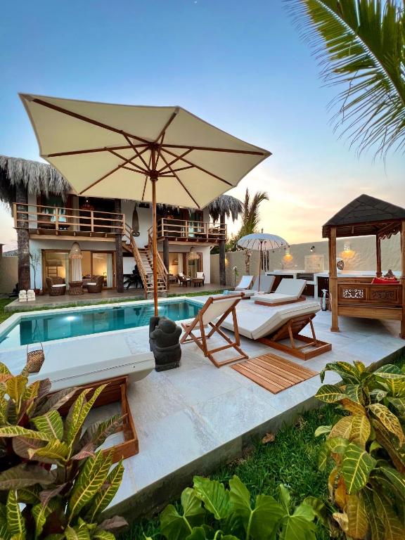 a villa with a swimming pool with chairs and an umbrella at Casa Bali Vichayito in Vichayito