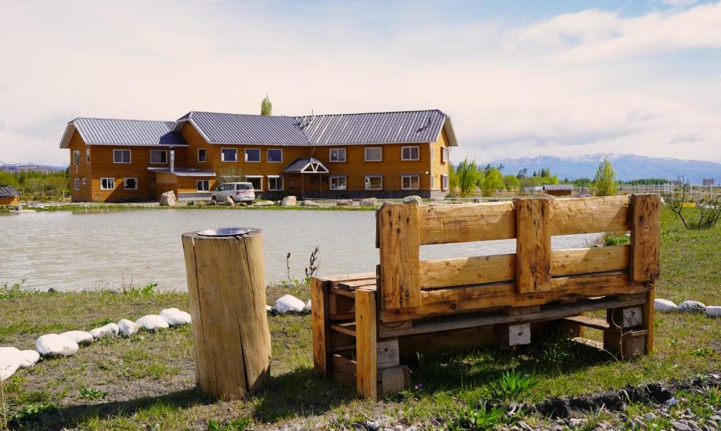 a wooden bench in the grass in front of a house at Hotel Posada del Río - Chile Chico in Chile Chico